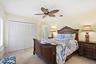 Neutral tile flooring, white louvered closet doors, and palm-leaf style ceiling fan
