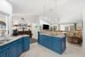 Kitchen featuring blue cabinetry, stone countertops, a large center island, tile flooring, and vaulted ceilings