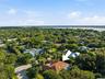 Aerial perspective of property featuring a tile roof, dual skylights, an enclosed rear pool, and mature landscaping