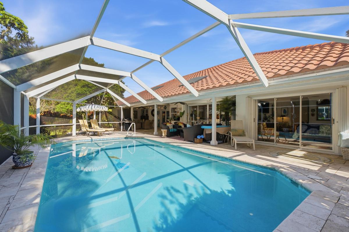 Screen-enclosed swimming pool featuring a paver stone deck, tile roof, and expansive sliding glass door entry