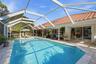 Screen-enclosed swimming pool featuring a paver stone deck, tile roof, and expansive sliding glass door entry