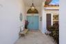 Covered entryway featuring stone-finish flooring, a double-door entry, a prominent arched transom window, a decorative hanging pendant light, and dark