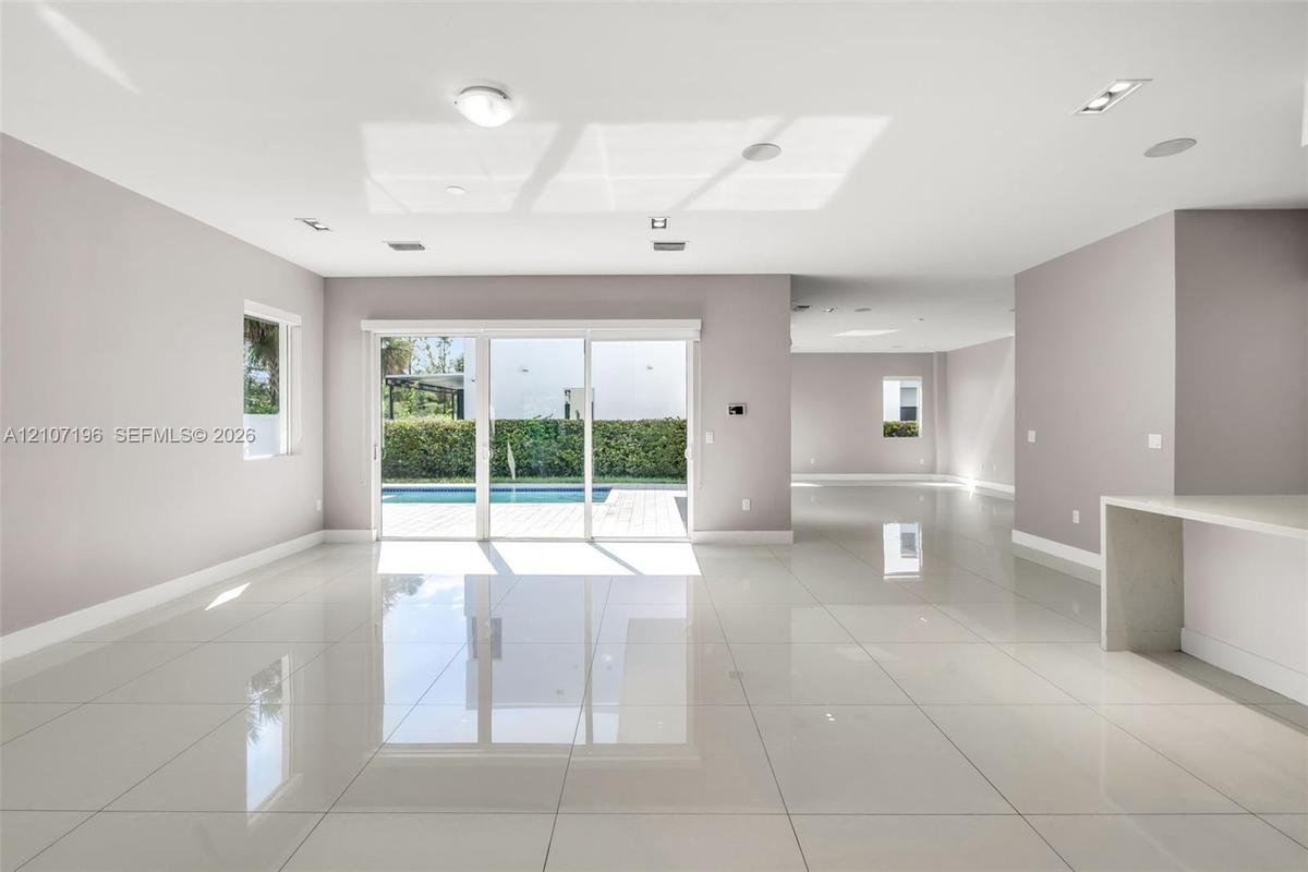 Open floor plan featuring oversized polished porcelain tile flooring, recessed lighting, and a waterfall-edge kitchen island