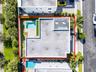 Aerial perspective featuring a private swimming pool, concrete paver patio, structural pergola, and perimeter hedge landscaping