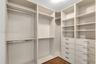 Custom walk-in storage featuring floor-to-ceiling shelving, integrated stainless steel hanging rods, and multiple soft-close drawers with metallic pul