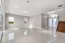 Open-concept interior featuring large-format tile flooring, recessed ceiling lighting, a wood-tread staircase with glass railing, and oversized glass 