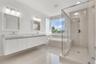 Floating dual vanity with rectangular vessel sinks, frameless glass-enclosed shower, soaking tub, and large-format tile flooring