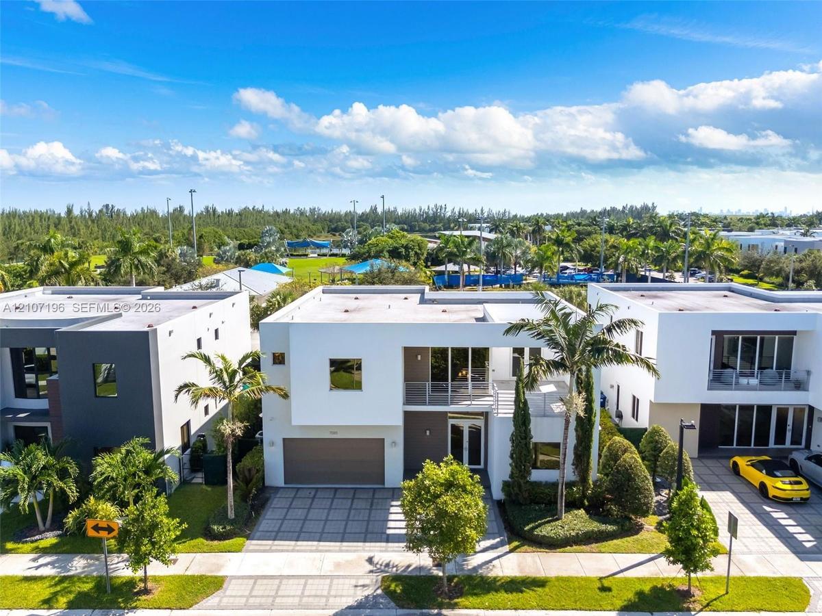 Modern two-story architectural exterior featuring a flat roofline, grid-patterned concrete paver driveway, attached two-car garage, second-level balco