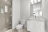 Bathroom featuring a modern floating vanity with a neutral-toned countertop, a glass-enclosed shower with tiled flooring, and a wall-mounted light fix