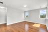 Neutral-toned interior space featuring wood-finish flooring, recessed lighting, and large windows providing natural illumination