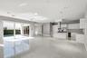 Open-concept space featuring polished tile flooring, white slab-front cabinetry, a kitchen island with stone-surface countertop, built-in stainless st