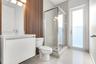 Bathroom featuring a white floating vanity, vertical wood-slat accent wall, glass-enclosed shower, polished tile flooring, and a glass-paneled exterio