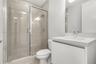 Bathroom featuring a sliding glass shower door, floor-to-ceiling wall tile, white vanity with a solid-surface countertop, and a built-in mirror
