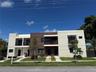 Contemporary two-story exterior featuring multi-textured facade, wood-finish paneling, private balconies with metal railings, and concrete walkways