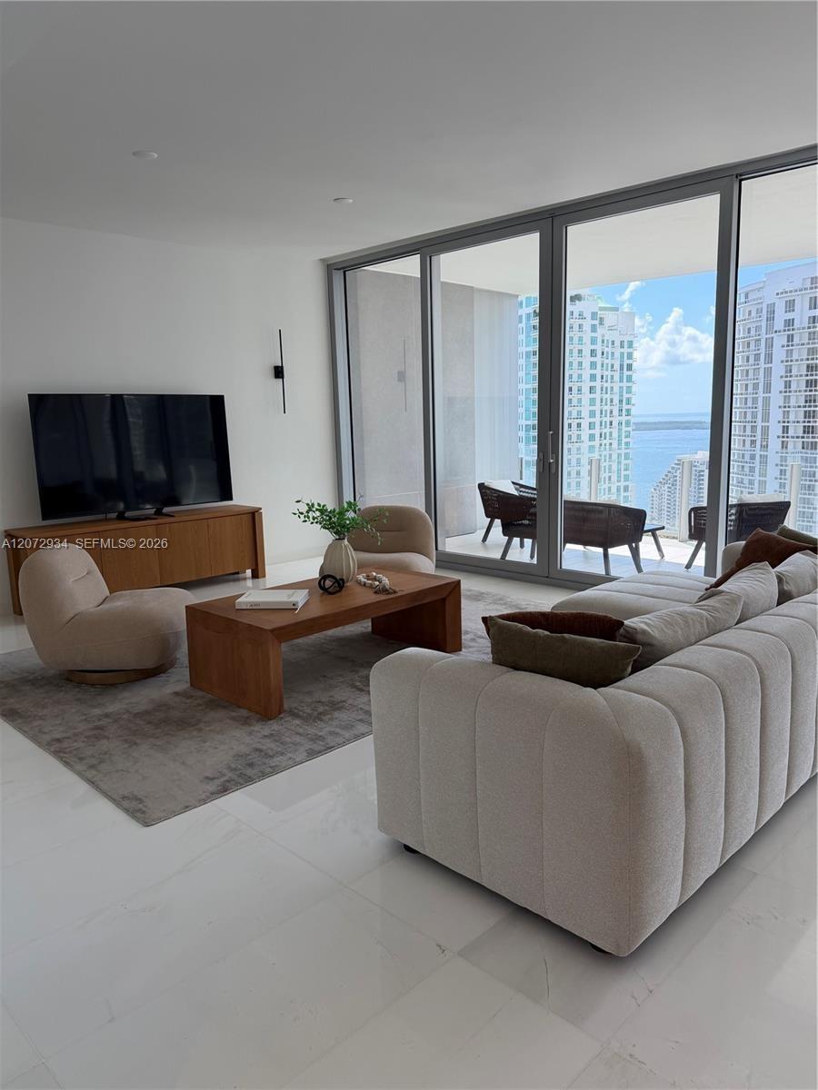 Floor-to-ceiling glass panel doors, polished stone-finish flooring, recessed lighting, and a private balcony