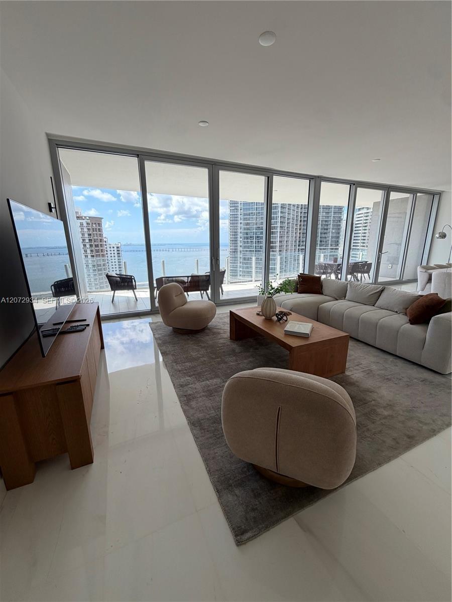 Floor-to-ceiling glass sliding doors, expansive balcony, polished stone flooring, and recessed ceiling lighting