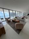 Floor-to-ceiling glass panel walls, polished stone flooring, and expansive exterior balcony access