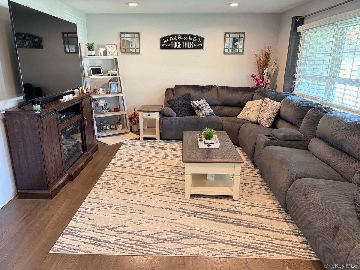 Wood-finish flooring throughout, featuring recessed lighting and a window with horizontal blinds