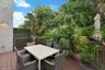 Elevated outdoor deck featuring composite wood-finish decking and a wooden balustrade, bordered by a privacy screen and mature perimeter vegetation