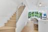 Staircase featuring wood-finish treads and metal horizontal railing, light wood-finish flooring, island with countertop and matte black faucet, and pe