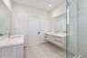 Floating dual vanities with white countertops and undermount sinks, full-width wall mirrors, large-format tile flooring, and a walk-in glass-enclosed 