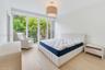 Floor-to-ceiling glass sliding doors, wood-finish flooring, metal balcony railing, and a drum-style pendant light fixture