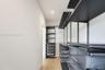 Custom storage system featuring matte black metal shelving, integrated pull-out wire baskets, hanging rods, and wood-finish flooring