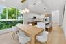 Kitchen featuring two-tone flat-panel cabinetry, a central island with a quartz countertop, wood-finish flooring, floor-to-ceiling windows, and contem