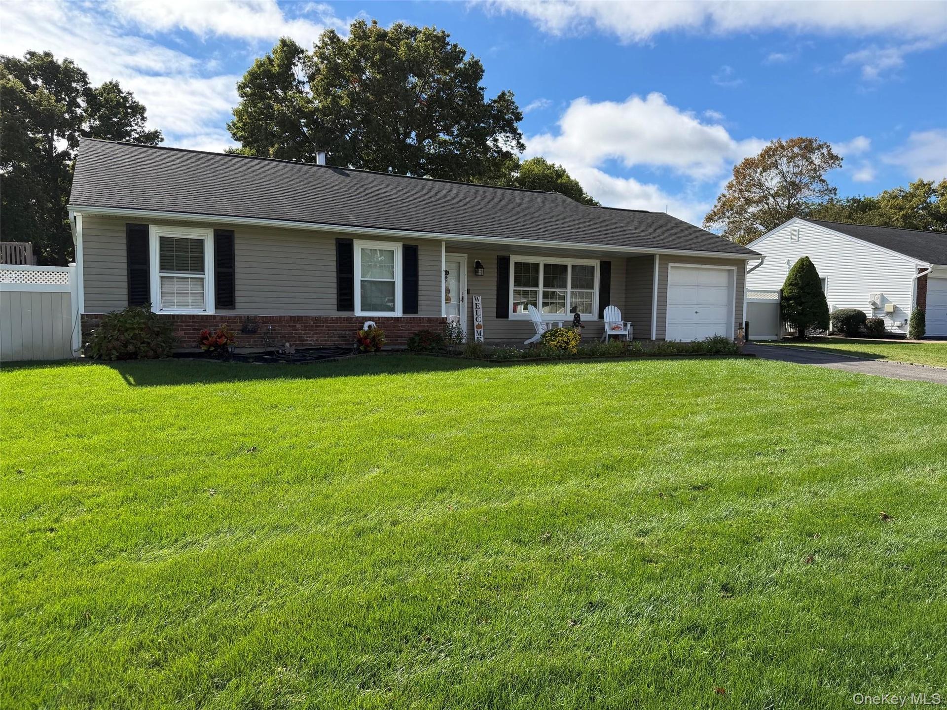Ranch-style residence featuring light gray siding, a dark shingle roof, and a white garage door.