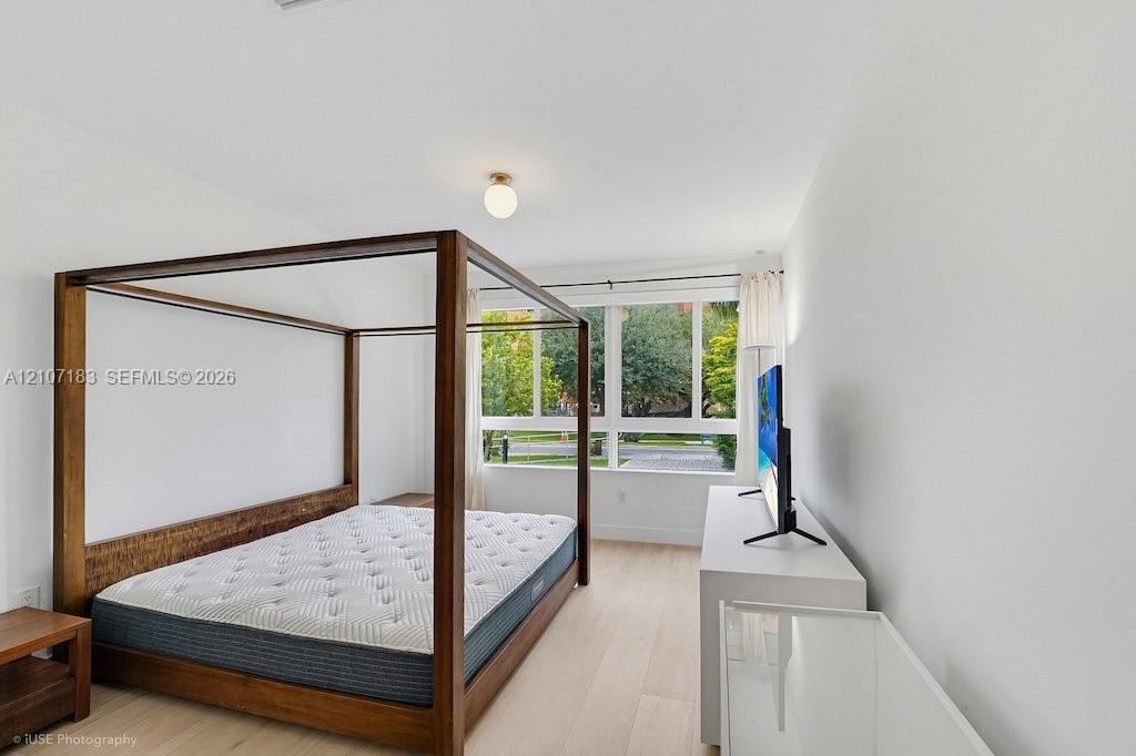 Large windows with grid detailing, wood-finish flooring, and a minimalist globe ceiling fixture