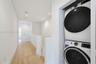 Stacked laundry appliance set featuring a front-load washer and dryer, wood-finish flooring, and recessed ceiling lighting