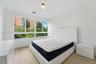 Floor-to-ceiling multi-panel windows, light-toned wood-finish flooring, and a modern globe flush-mount light fixture
