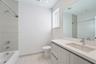 Modern vanity featuring a light-toned wood-finish cabinet and integrated solid-surface countertop with an undermount basin