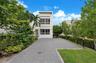 Contemporary architectural exterior with smooth white stucco facade, multi-level horizontal windows, and a paved brick driveway