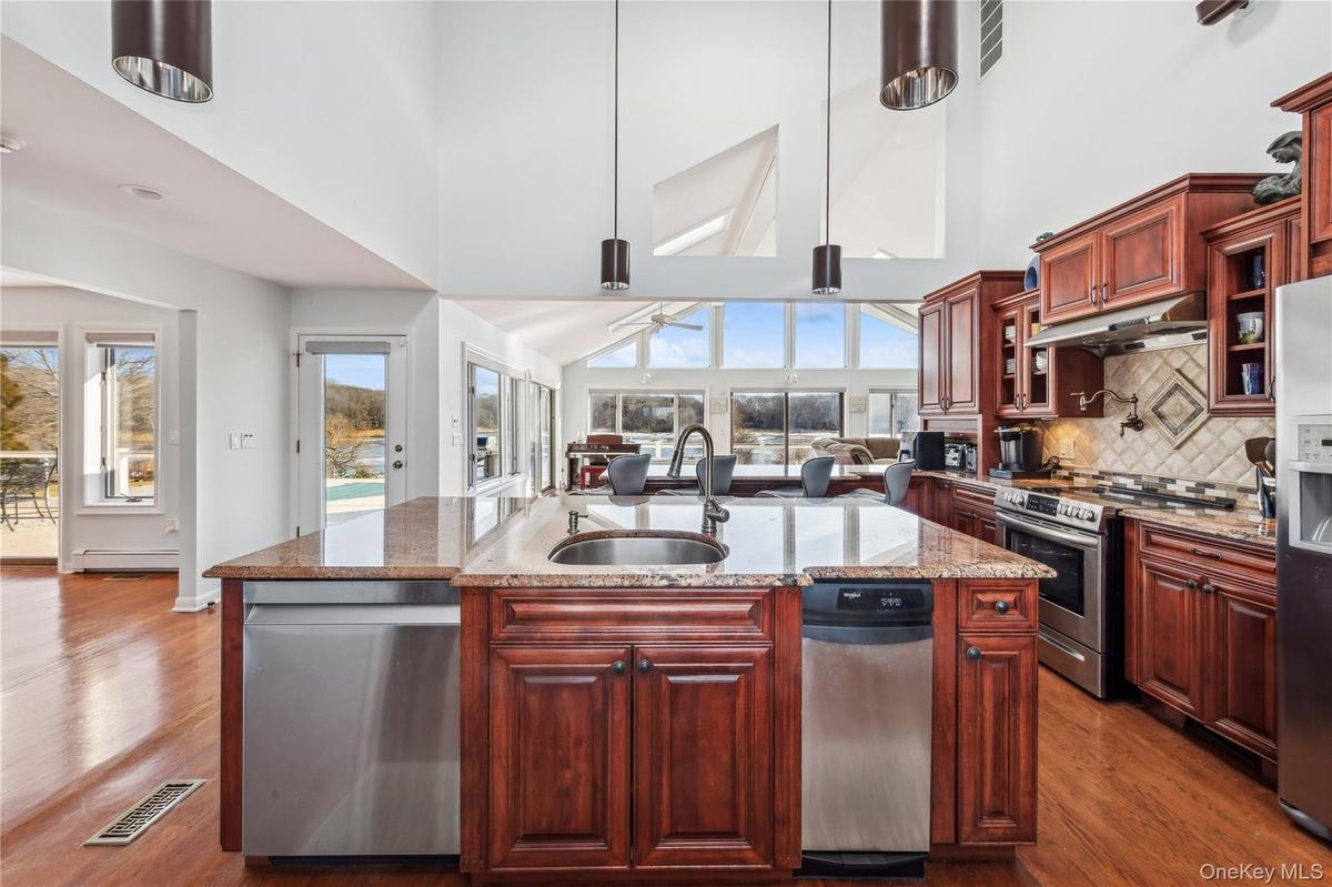 Kitchen with sink, an island with sink, pendant lighting, stainless steel appliances, and hardwood / wood-style floors