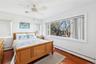 Bedroom with dark hardwood / wood-style flooring, a baseboard heating unit, and ceiling fan