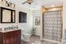 Bathroom featuring hardwood / wood-style floors, curtained shower, vanity, ceiling fan, and toilet