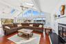 Living room with dark wood-type flooring, a skylight, ceiling fan, and a water view