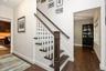 Hardwood flooring, painted white baseboards, traditional staircase with wood-finish handrail, and white risers