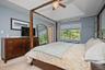 Tray ceiling with a decorative ceiling fan, window with roller shades, and light blue wall paint