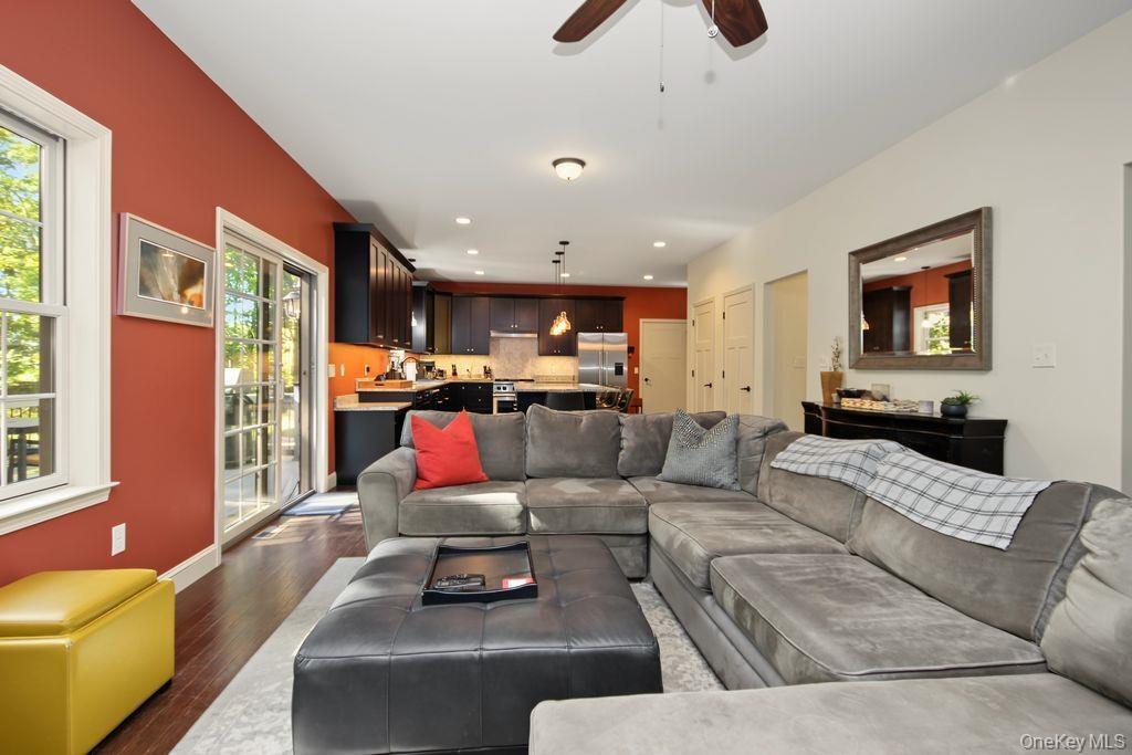 Recessed lighting and a ceiling fan illuminate a living area with wood-finish flooring