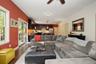 Recessed lighting and a ceiling fan illuminate a living area with wood-finish flooring