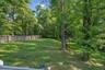 Expansive rear yard featuring a manicured lawn, established picket fencing, and mature trees