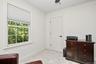 Double-hung window with white trim, white paneled door with black hardware, and light-colored carpeting