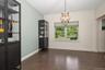 Dining room with vaulted ceiling with a chandelier, wood-finish flooring, and a large window with roller shades
