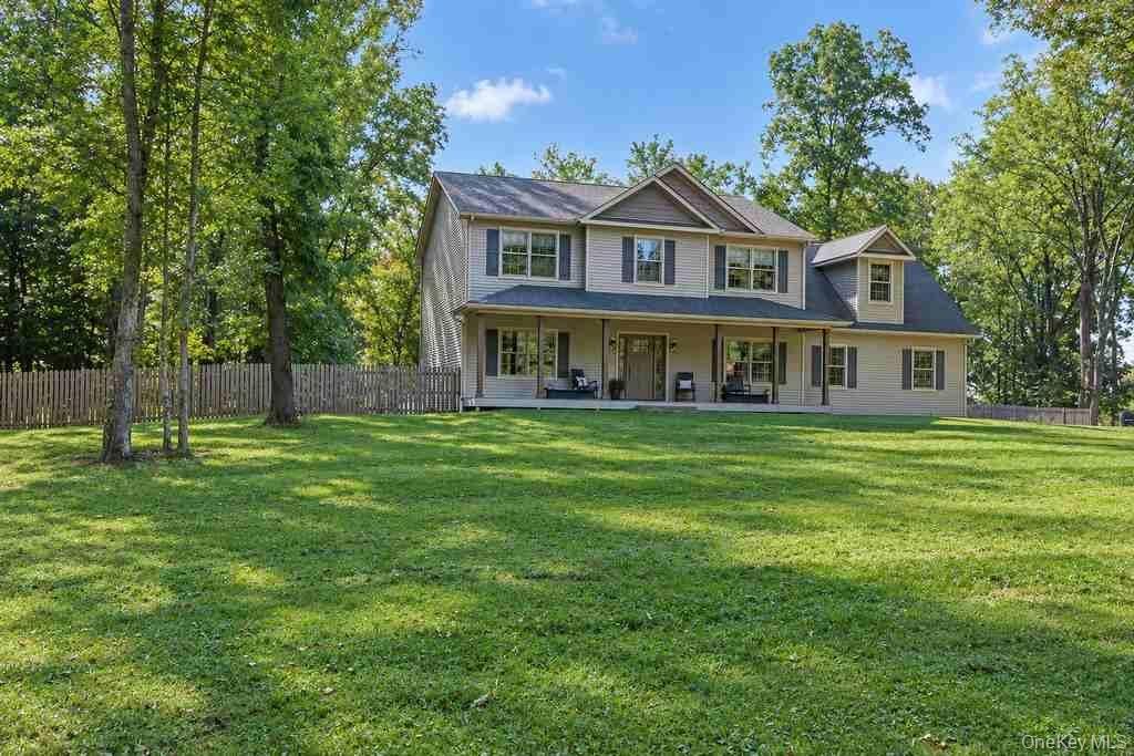 Expansive front lawn with mature trees and a picket fence