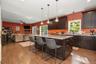 Open-concept kitchen and living area featuring wood-finish flooring, dark wood cabinetry, a center island with a light-toned countertop, and recessed 