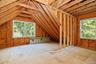Unfinished attic space with exposed wood framing, two new windows, and oriented strand board flooring