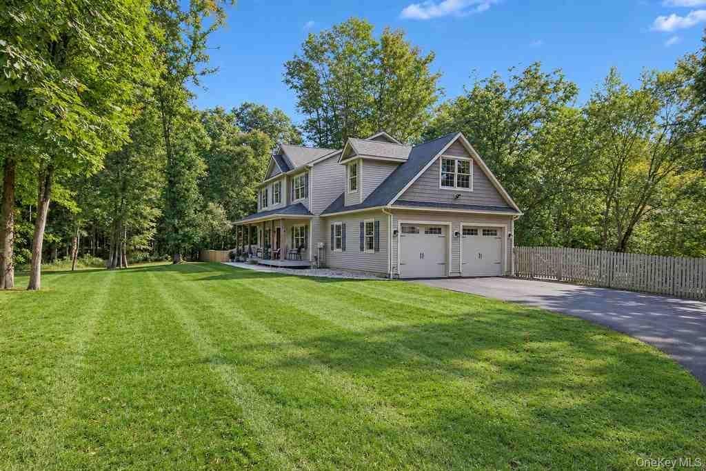 Two-story property featuring a covered porch, attached two-car garage, dormer windows, and a paved driveway