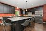 Spacious kitchen featuring dark cabinetry, stainless steel appliances, a large center island with a stone countertop, and wood-finish flooring